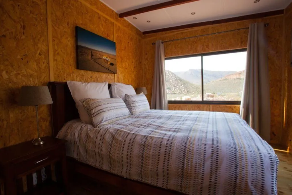 Cozy bedroom with large window wooden walls and striped bedding