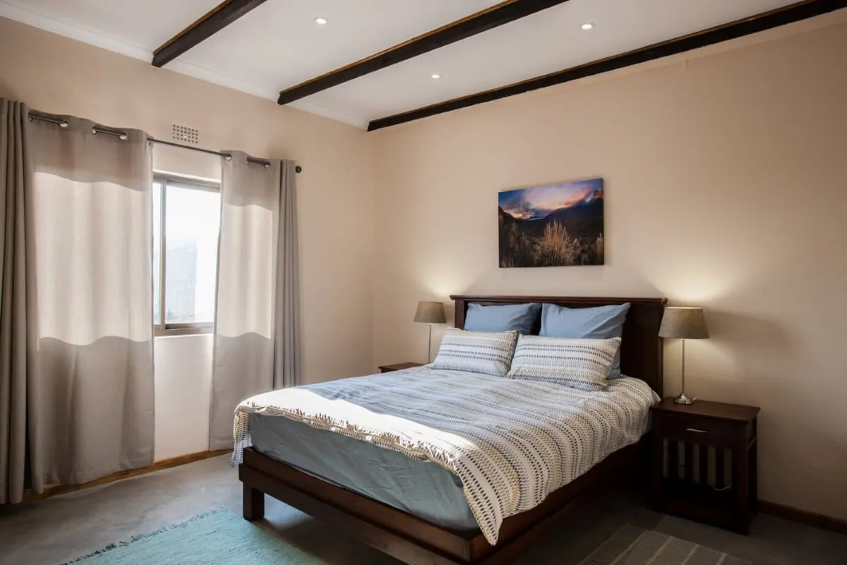 Cozy bedroom with a bed two bedside tables and a naturethemed painting