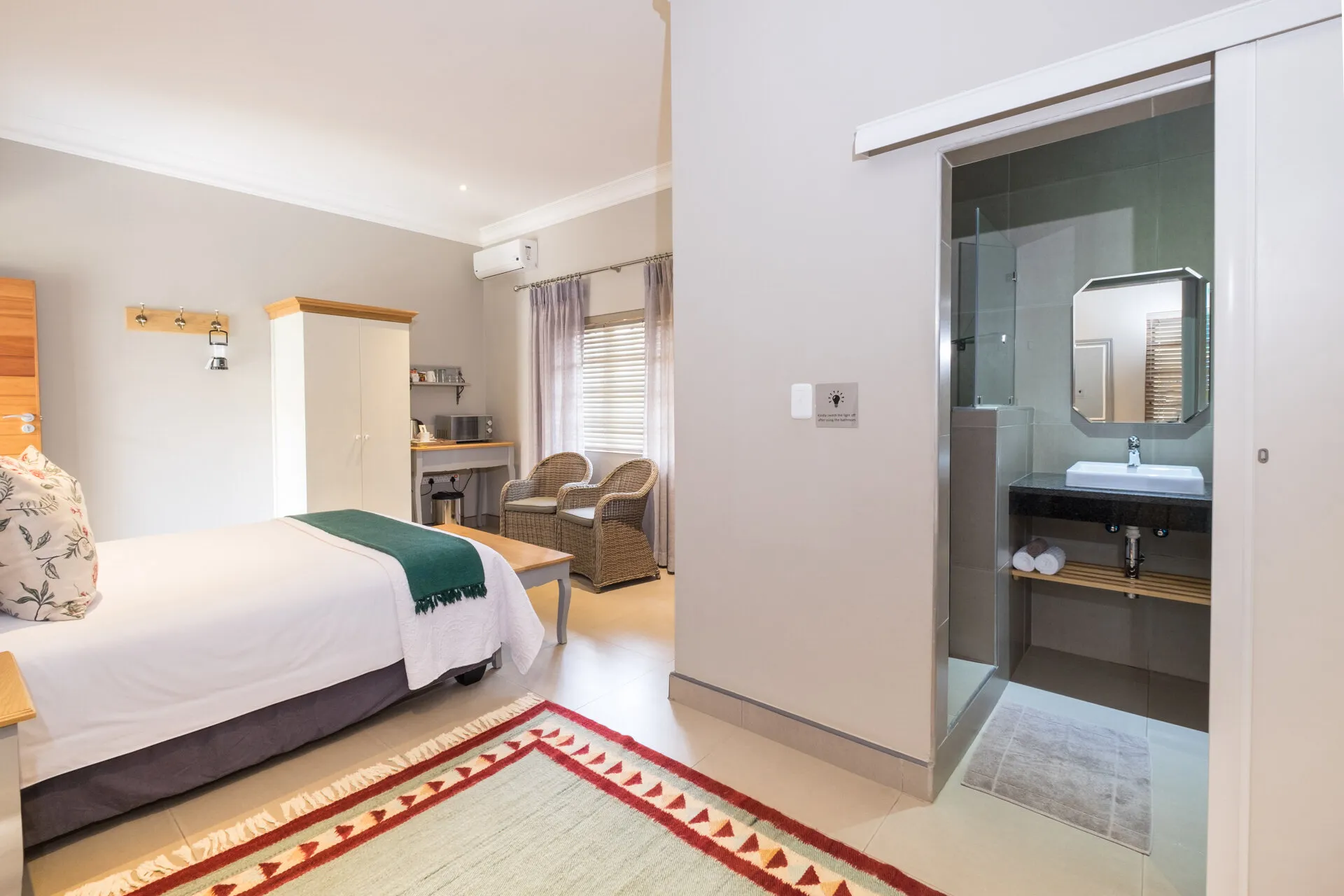 Modern hotel room with bed desk and open bathroom area with sink