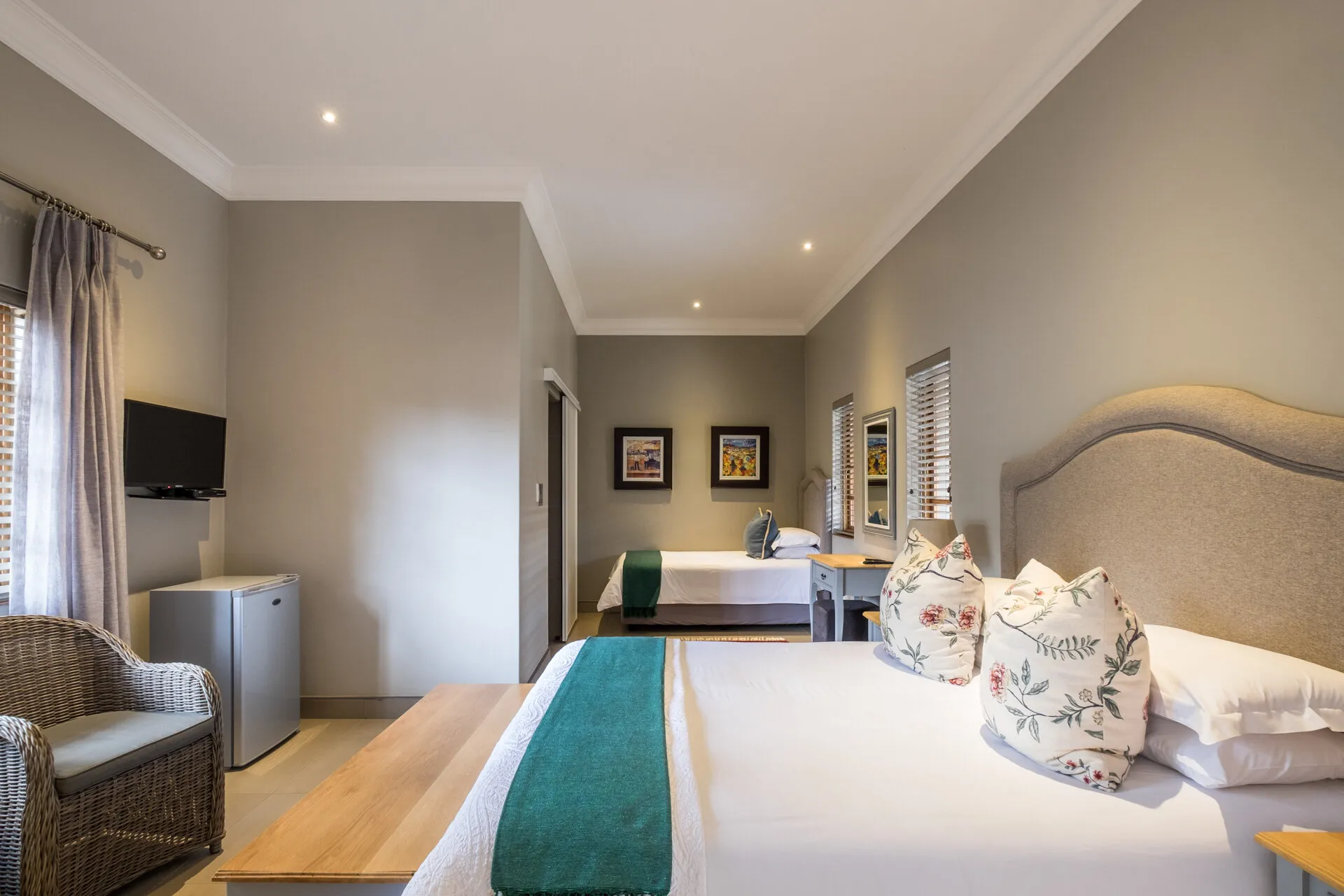 Hotel room with two beds armchair TV and artwork on the walls