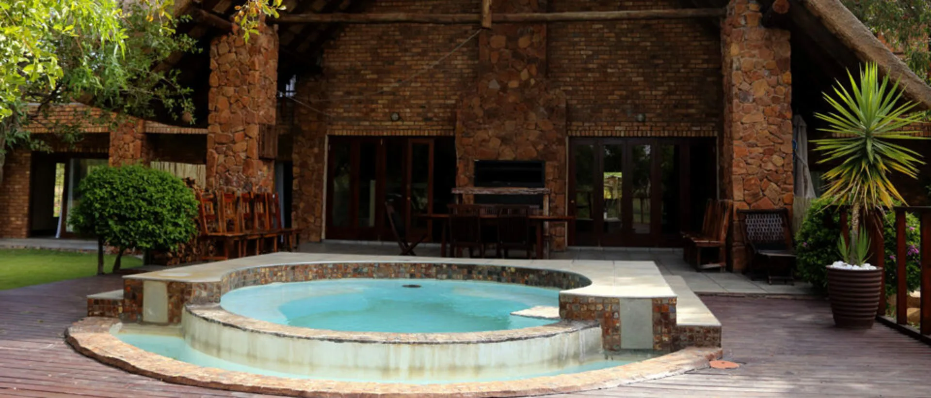 Outdoor patio with hot tub dining area and rustic stone building in background