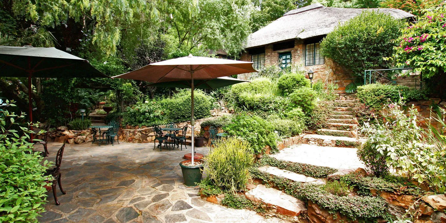 Stone house with garden patio and umbrellacovered seating area