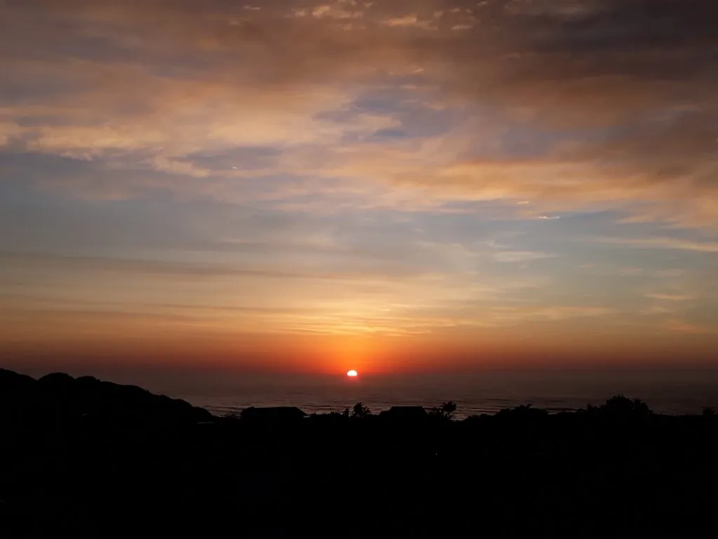 Sunset over the ocean with a silhouette of land in the foreground