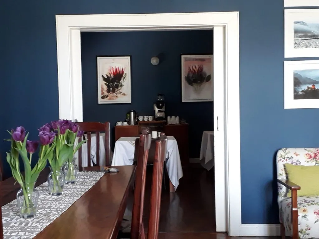 Dining room with wooden table chairs and floral paintings on blue walls