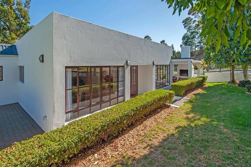 White house with large windows green hedge and wellmaintained lawn