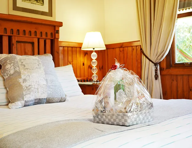 Gift basket on a bed in a cozy woodenpaneled bedroom with soft lighting