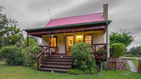Cozy cottage with red roof wooden porch and lush greenery in a garden