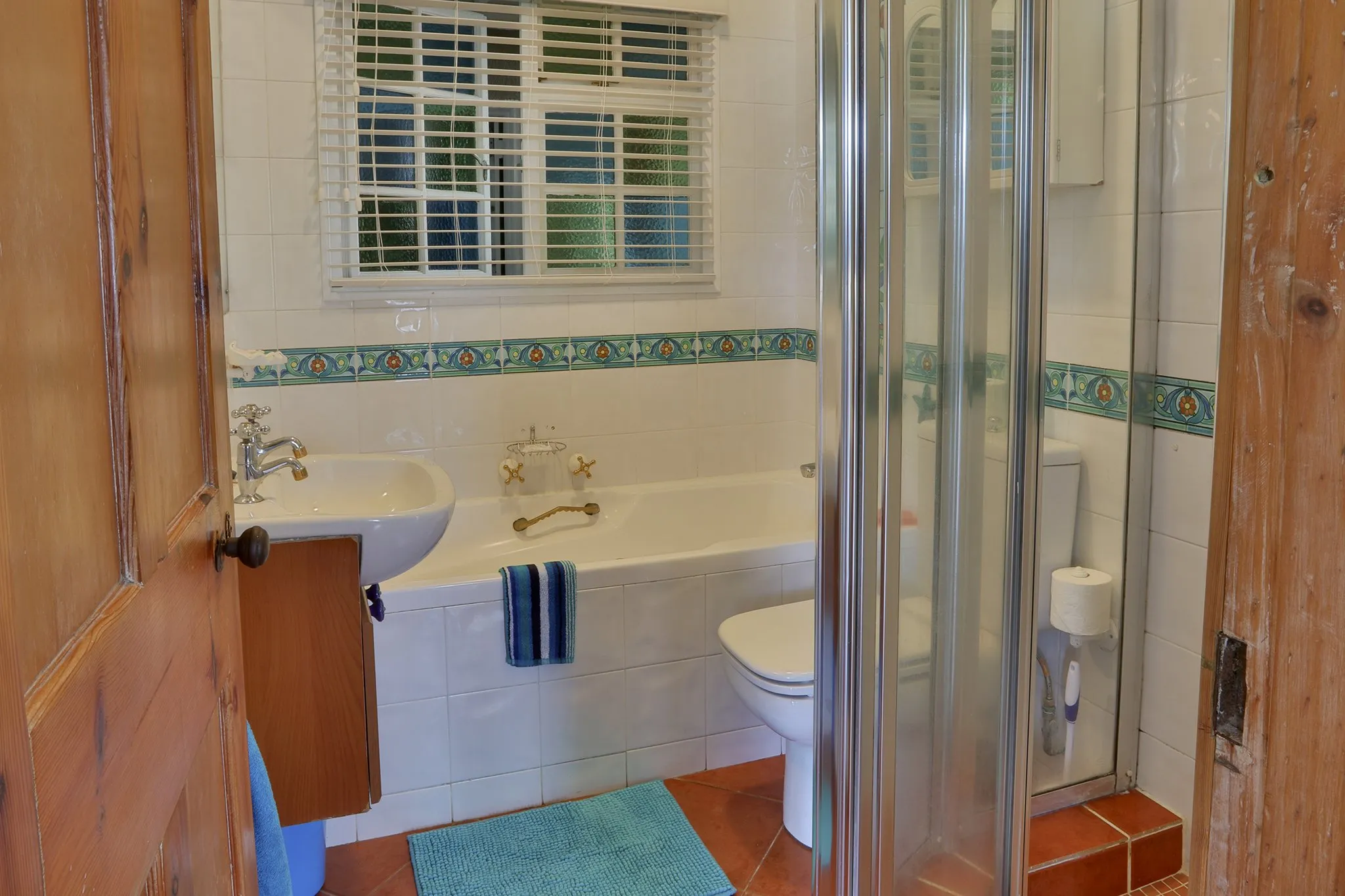 Small bathroom with bathtub toilet and window featuring blue and white tiles
