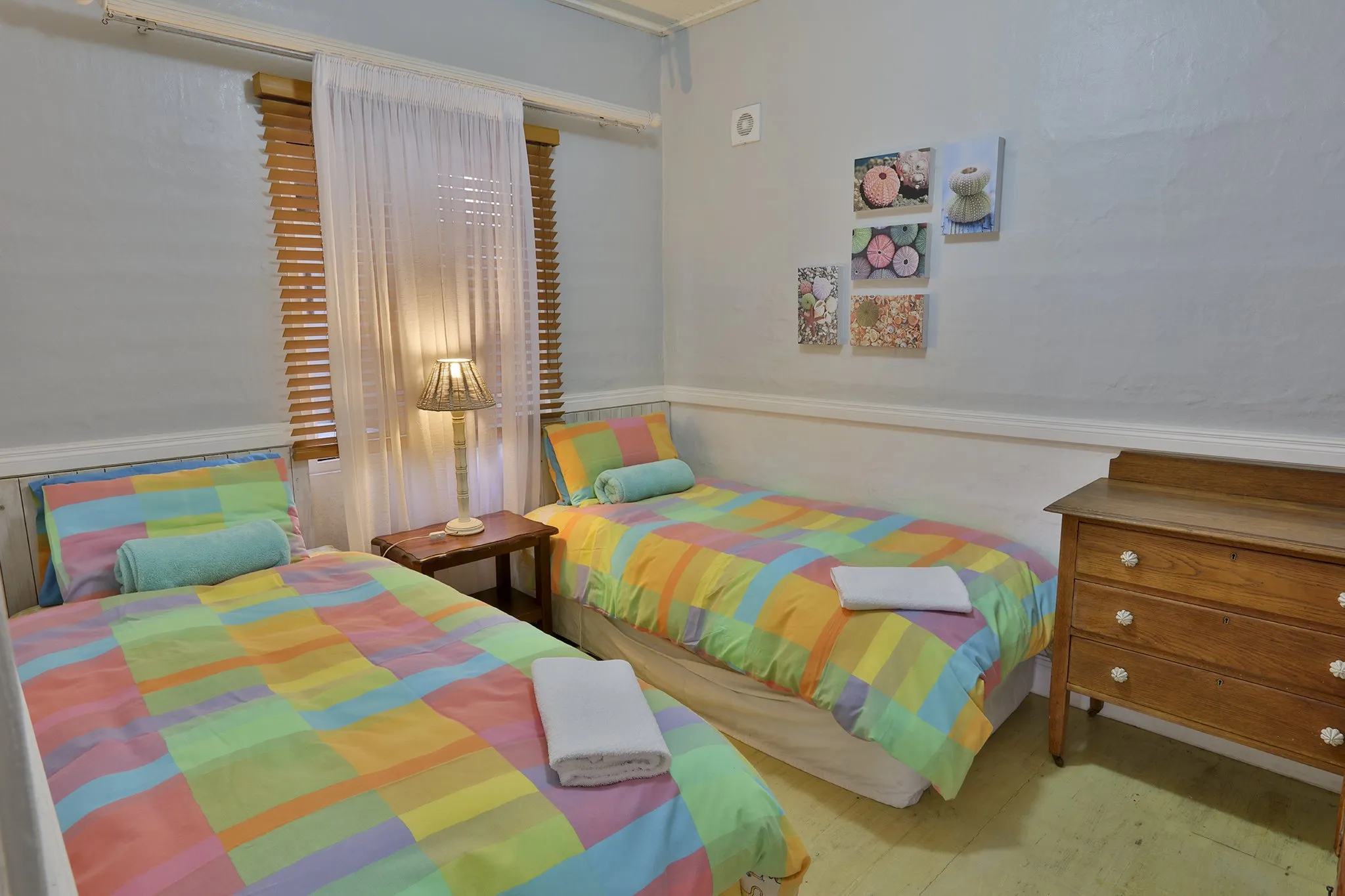 Brightly colored twin beds in a cozy bedroom with wooden furniture and decor