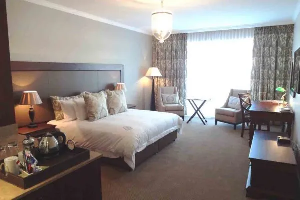 Hotel room with large bed desk chairs and window with curtains
