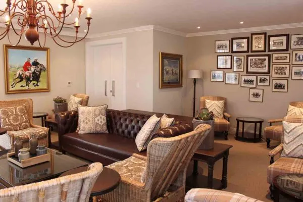 Cozy living room with brown leather sofa armchairs and framed pictures on wall