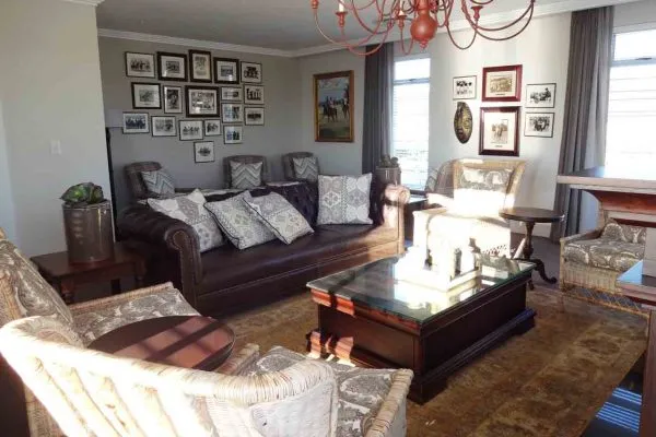 Cozy living room with brown leather sofa armchairs and framed pictures on walls