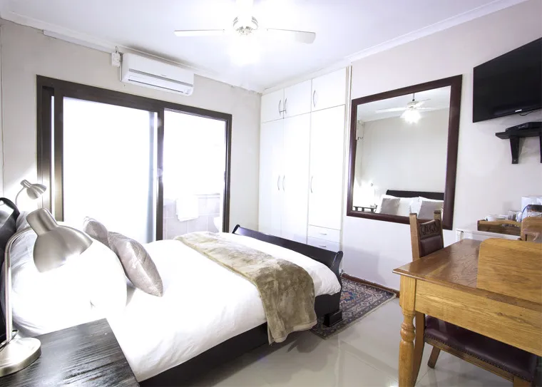 Modern bedroom with bed desk mirror and sliding glass door to balcony
