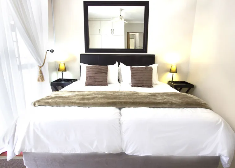 Cozy bedroom with a large bed white bedding and a mirror above the headboard