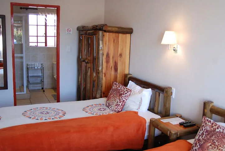 Cozy bedroom with two beds wooden furniture and a mirror reflecting a bathroom