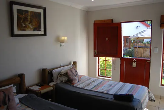 Bedroom with two single beds open red door and a wall painting