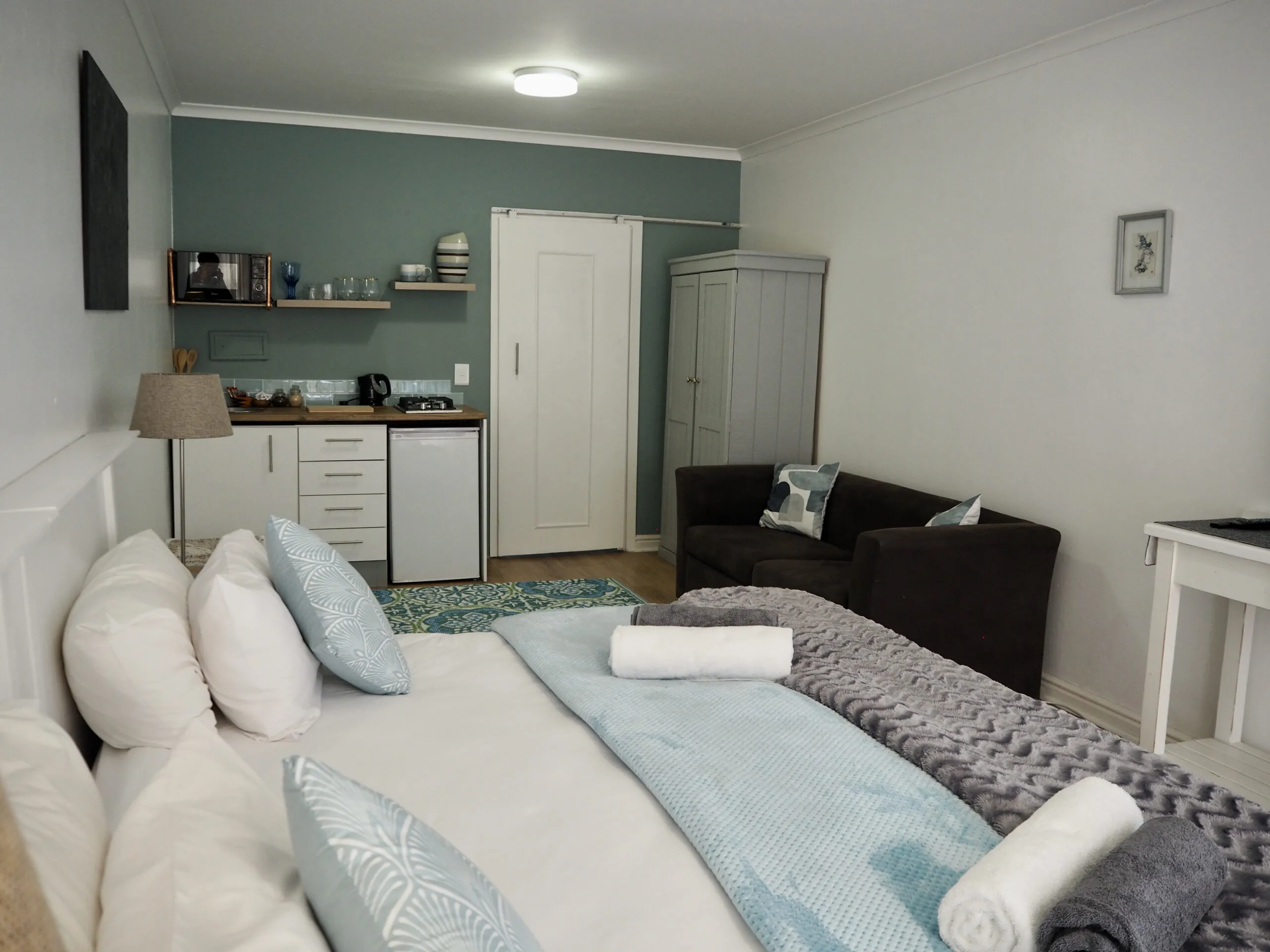 Cozy bedroom with kitchenette sofa and neatly made bed with towels
