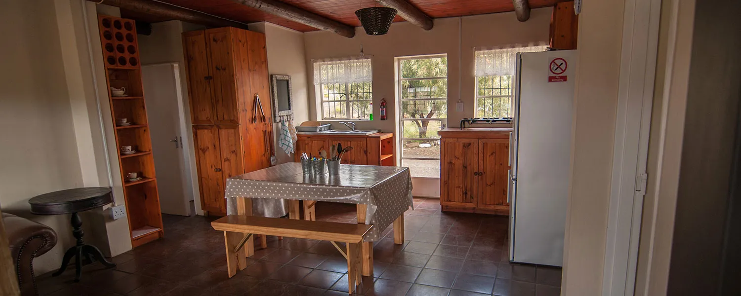 Wooden kitchen with dining table cabinets and refrigerator in a cozy setting