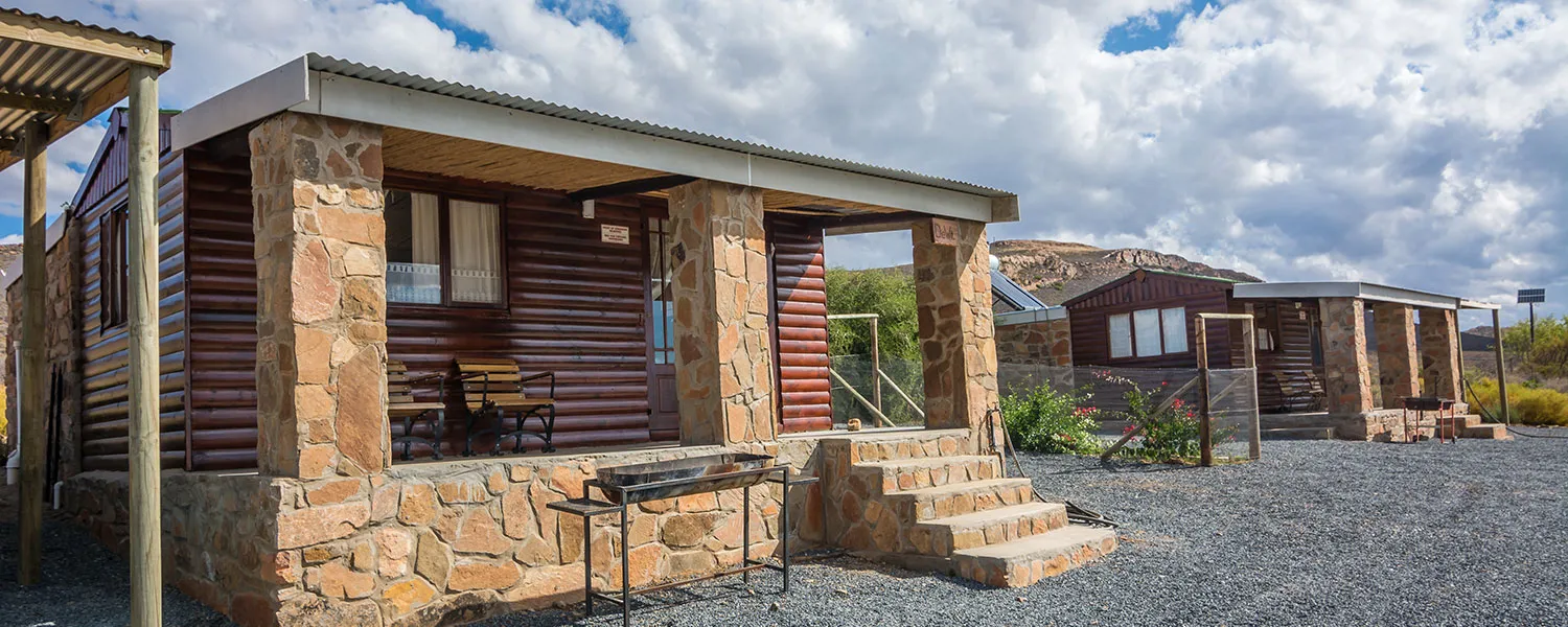 Stone and wood cabins with verandas in a rocky outdoor setting