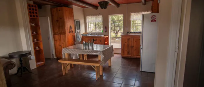 Wooden kitchen with table benches cabinets and refrigerator in a rustic setting