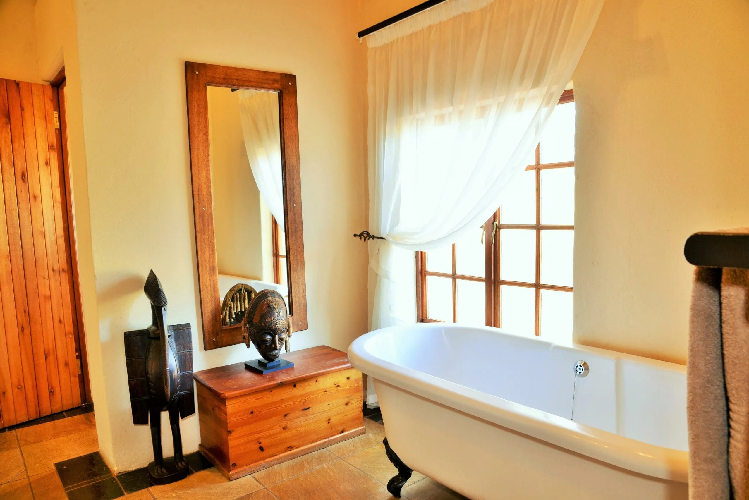 Wooden bathroom with a white bathtub mirror and wooden furniture