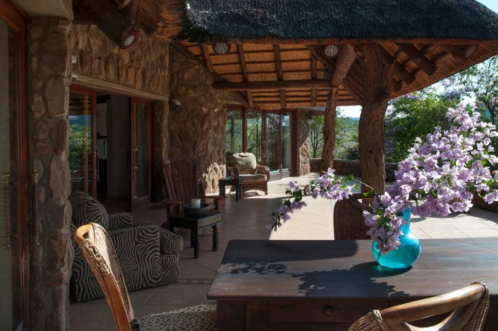 Wooden patio with stone walls chairs and a table with a blue vase