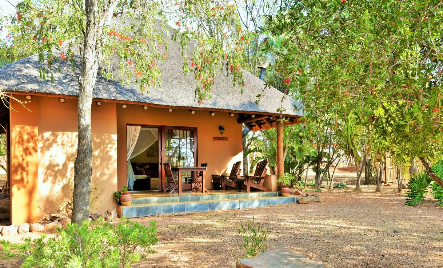 A cozy thatchedroof cottage surrounded by trees in a natural setting