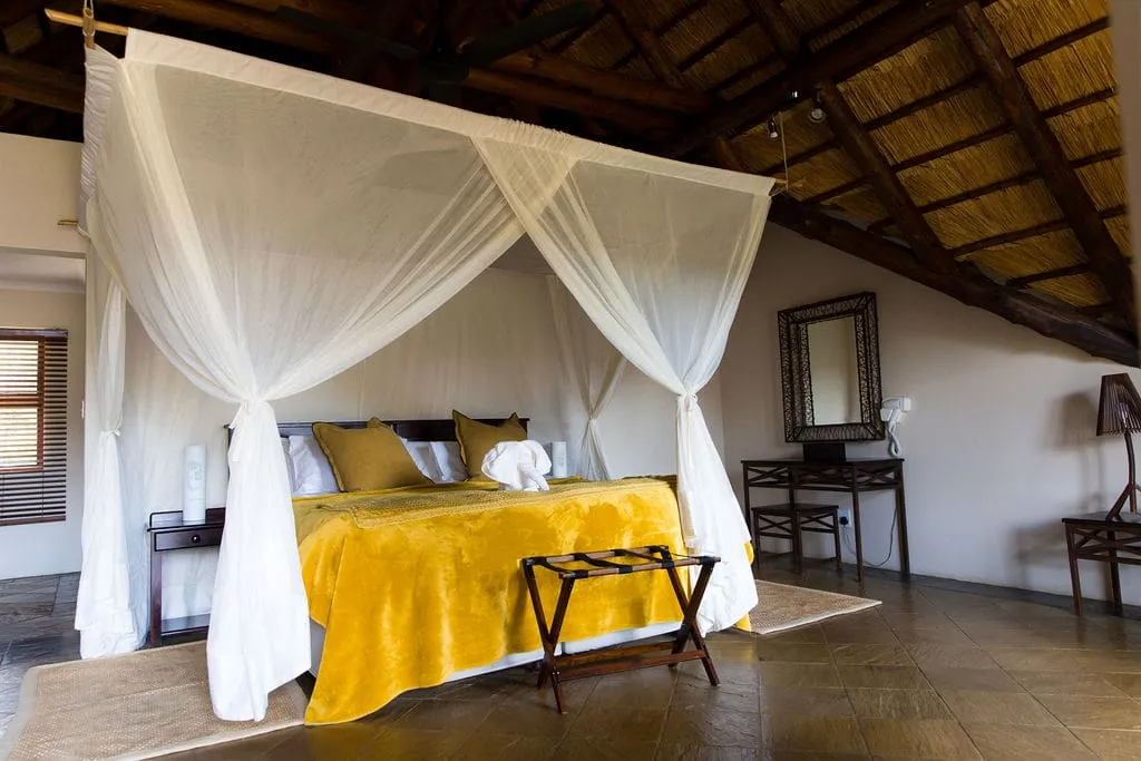 Cozy bedroom with a large bed yellow blanket and mosquito netting