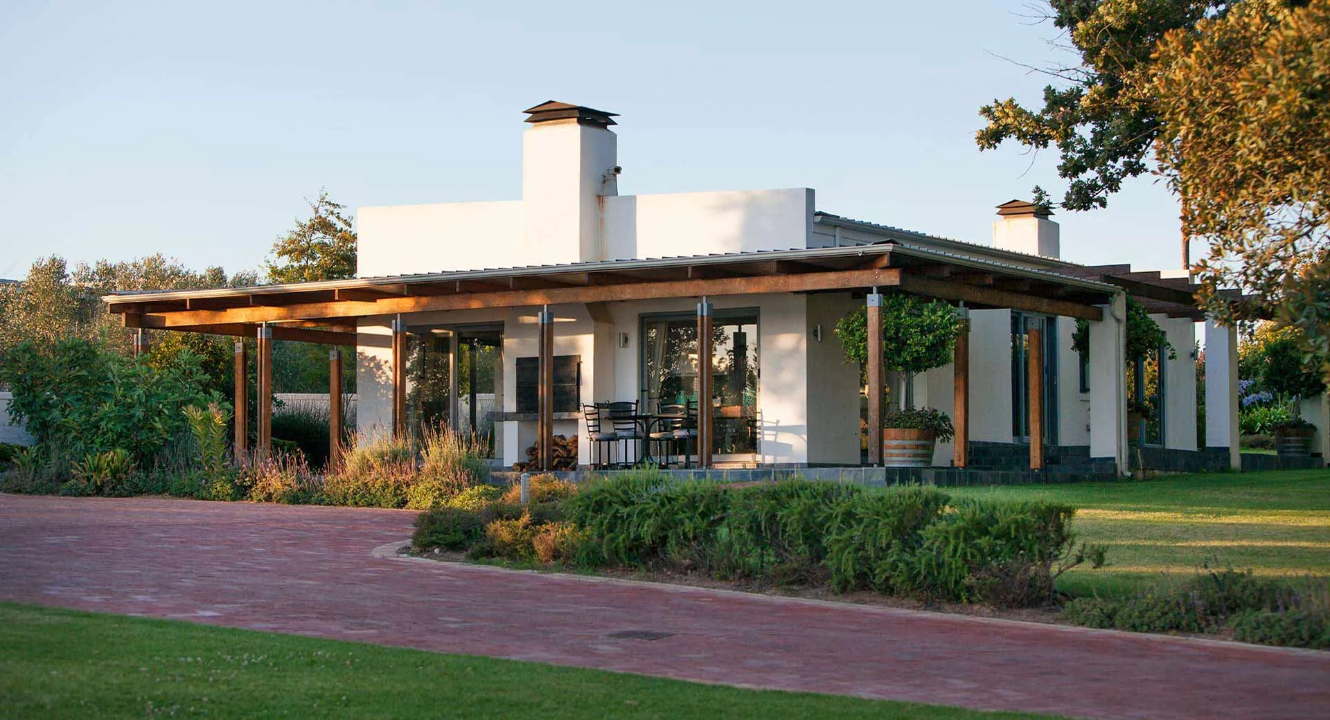 Modern white house with large windows and a covered patio surrounded by greenery