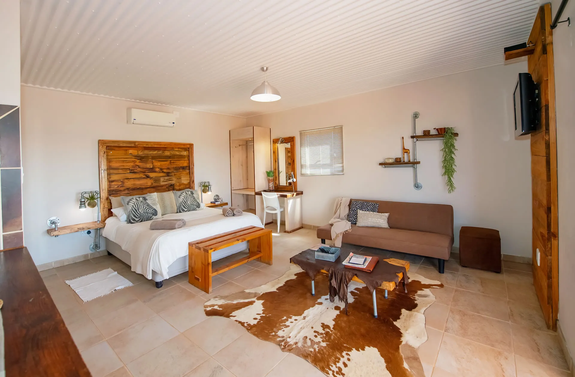 Cozy bedroom with wooden bed sofa cowhide rug and modern decor