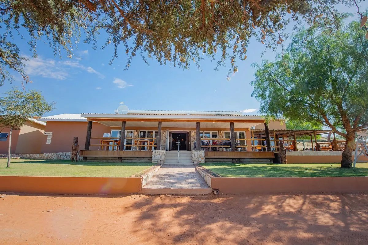 Singlestory building with a veranda surrounded by trees and a dirt path