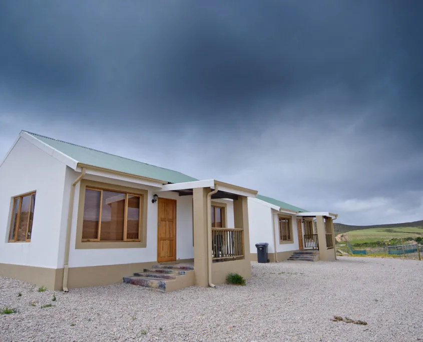 White house with green roof under a cloudy sky gravel foreground