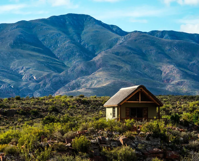Small cabin in a mountainous landscape with green shrubs