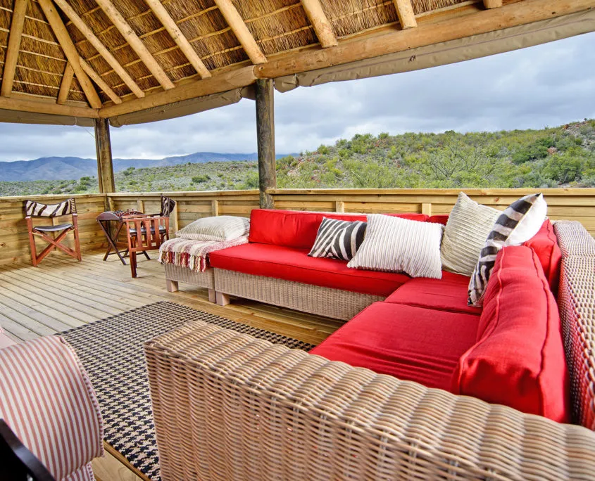Outdoor seating area with red cushions under a wooden roof scenic background