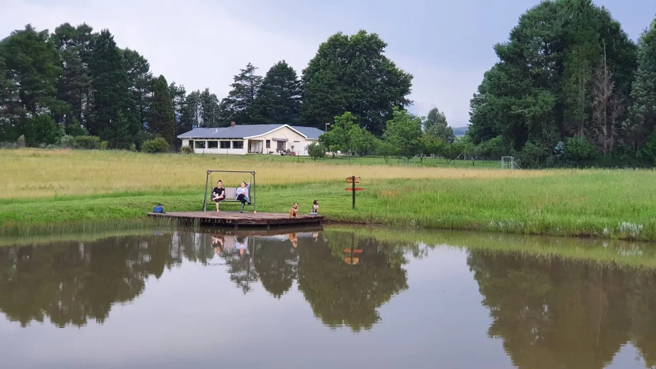 A group of people on a dock by a pond with a house in the background