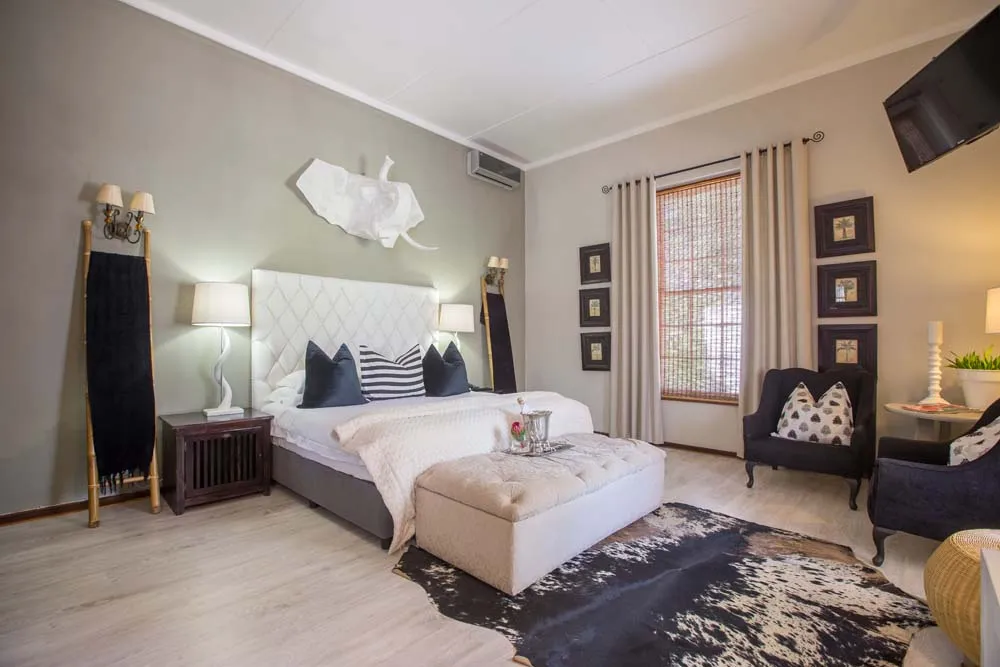 Modern bedroom with large bed seating area and wallmounted TV