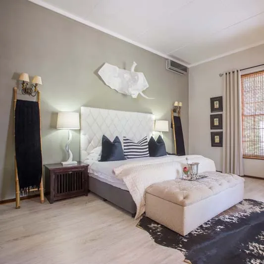 Modern bedroom with white bed wooden floor and decorative wall art