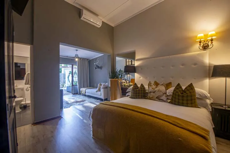 Modern bedroom with large bed ensuite bathroom and living area in background