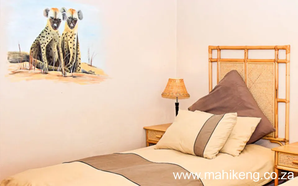 Bedroom with a bed side tables and a wall painting of two hyenas