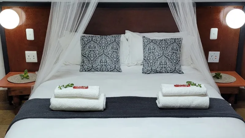 A neatly made bed with decorative pillows and towels in a bedroom