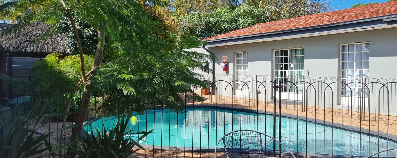 Swimming pool in a backyard with a house and surrounding greenery