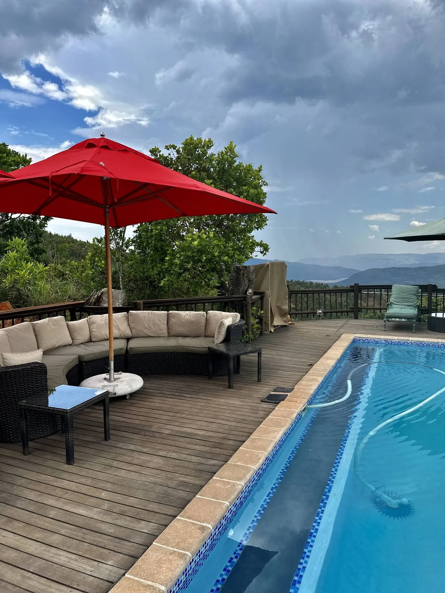 Wooden deck with red umbrella lounge chairs and pool overlooking mountains