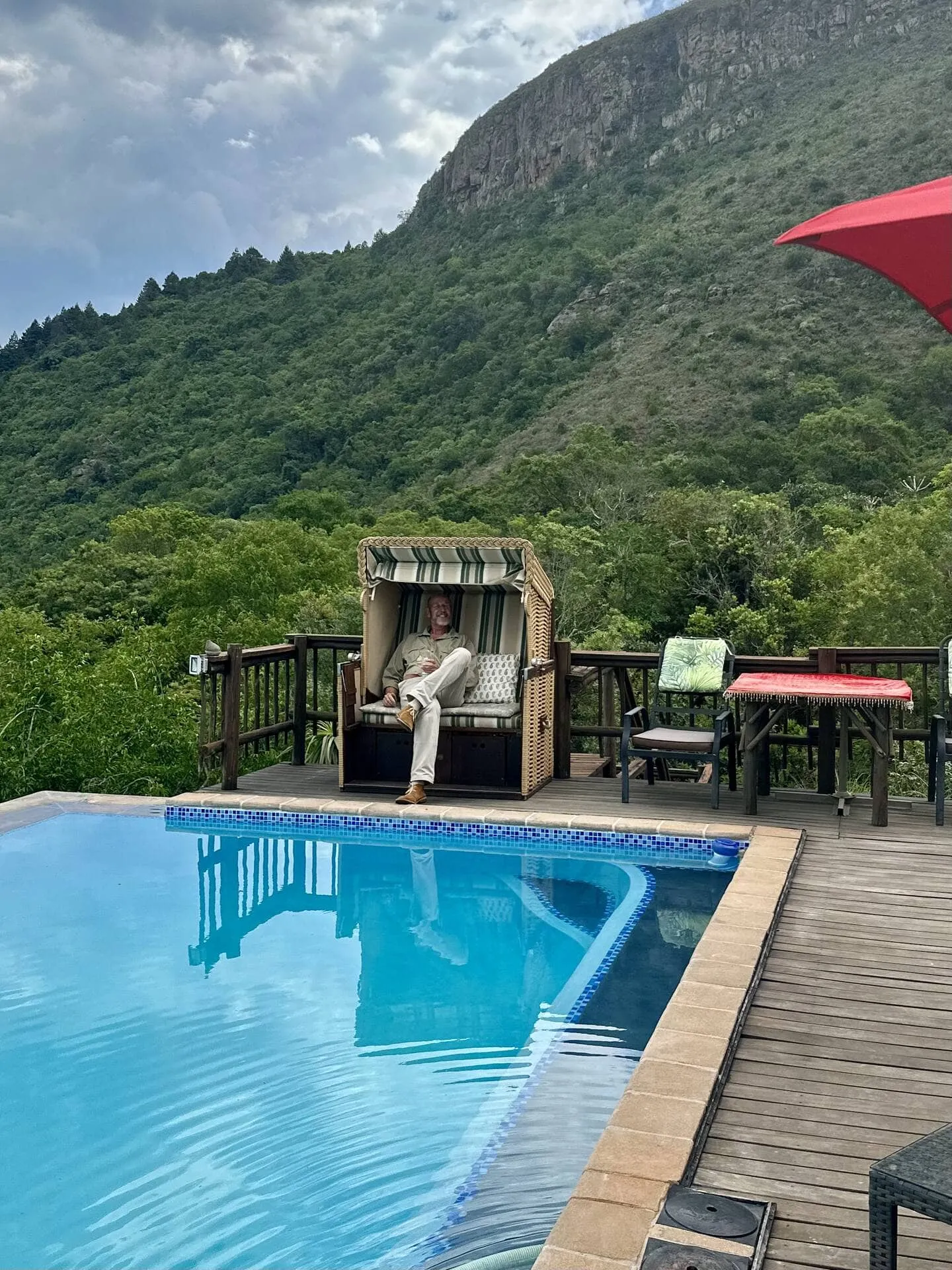 Person relaxing in a poolside chair with a scenic mountain backdrop