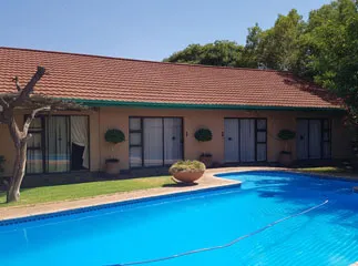 House with redtiled roof large windows and a swimming pool in front