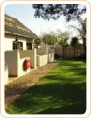 House with a red fire extinguisher and green lawn in a sunny garden