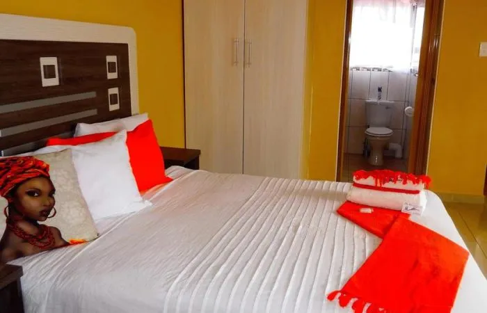 Bedroom with a bed red and white pillows and an open bathroom door