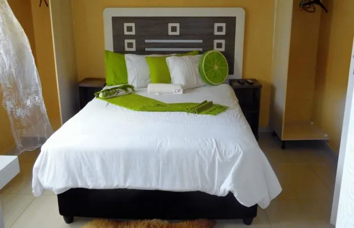 Bedroom with a bed decorated with green and white pillows and bedding
