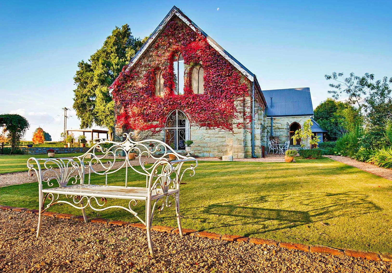 Stone house with ivy white bench in garden sunny day