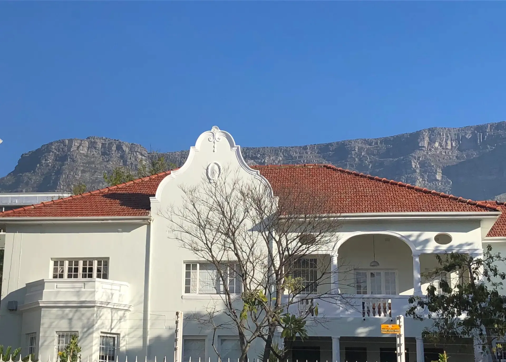 White building with redtiled roof and mountains in the background