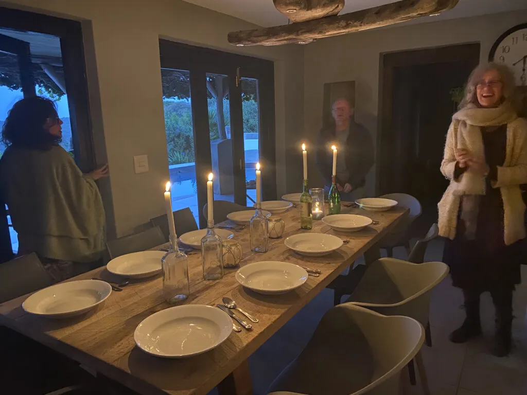 Three people standing around a set dining table with candles in a cozy room